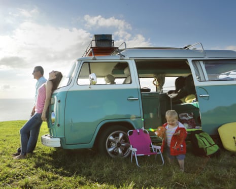 Family relaxing with camper in field by sea