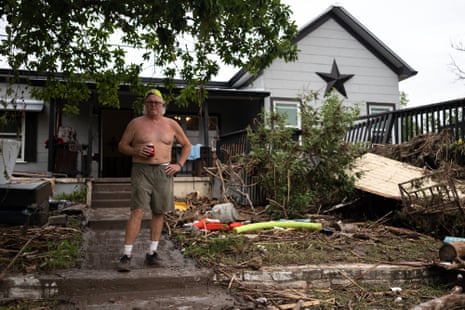 Kyle Hammock stands in front of his damaged home on the bank of Guadalupe River after clearing debris from inside his home.