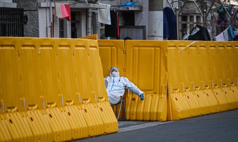 A worker in PPE guards the entrance to a neighbourhood in lockdown in Jing'an district, Shanghai, on 29 March 2022.