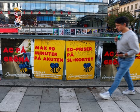 A man walks past posters for the Sweden Democrats on a bridge