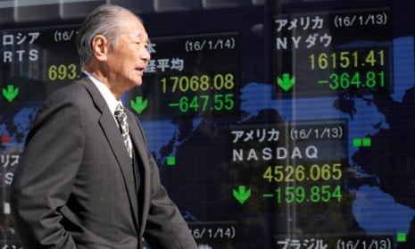 A man walks past a monitor displaying information of global markets at a securities branch office in Tokyo, Japan