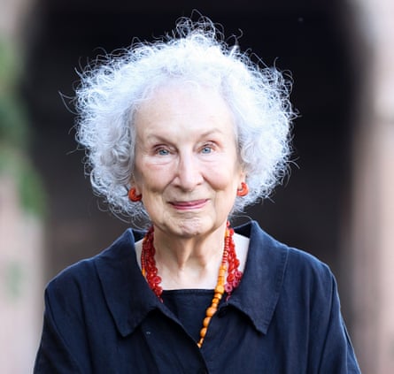 Margaret Atwood, smiling, in a collared jacket with two large-beaded necklaces