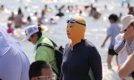 A woman wears a facekini at a crowded beach
