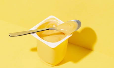 Yogurt cup on pastel yellow background.