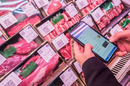 A customer looks at the logistic information on his smartphone after scanning a QR code on a box of imported beef at a supermarket in Hangzhou.