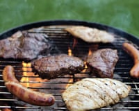 Closeup of sausages and beef grilling on an outdoor grill in a park