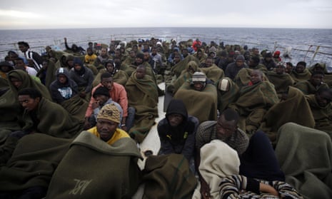 Migrants sit on the deck of the Belgian navy vessel Godetia