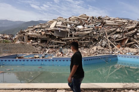 A person walks past the debris of buildings that collapsed in the earthquakes.