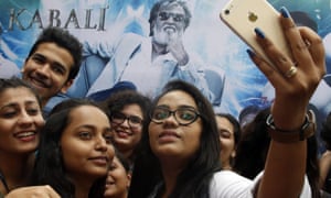 Fans take a selfie in front of a Kabali poster