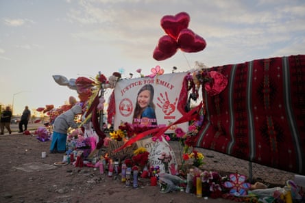 a memorial on a fence with red balloons, a large banner with a photo of a girl, and many candles.