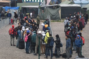People queue outside a hangar where they will be sorted into groups and put on buses for shelters across France, as part of the full evacuation of the Calais refugee camp.