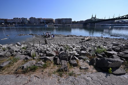 A group of people stands by the water’s edge of the Danube