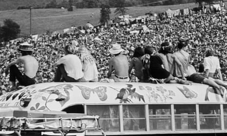 Fans sitting on top of a painted bus at Woodstock, 1969. 