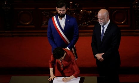 Caroline Toha, minister of interior, signs the constitution draft as Chile’s president, Gabriel Boric, and minister secretary general, Álvaro Elizalde, look on, in Santiago on 7 November. 