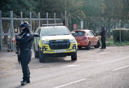 Police stop a vehicle at the side of the road, alongside the airbase's security fence