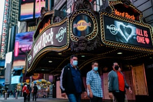 Pedestrians wearing face masks walk in front of the Hard Rock Cafe in Times Square, New York, on 10 November.