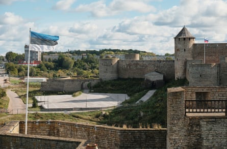 An Estonian flag flies in the foreground, while in the near distance a Russian flag flies on a castle