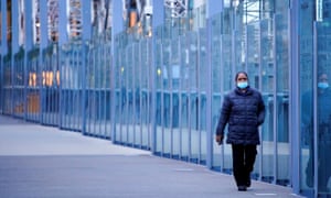 A woman wearing a protective face mask walks along a deserted city bridge during morning commute hours on the first day of a lockdown as the state of Victoria looks to curb the spread of coronavirus.