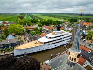A mega yacht dwarfs the town through which it is piloted
