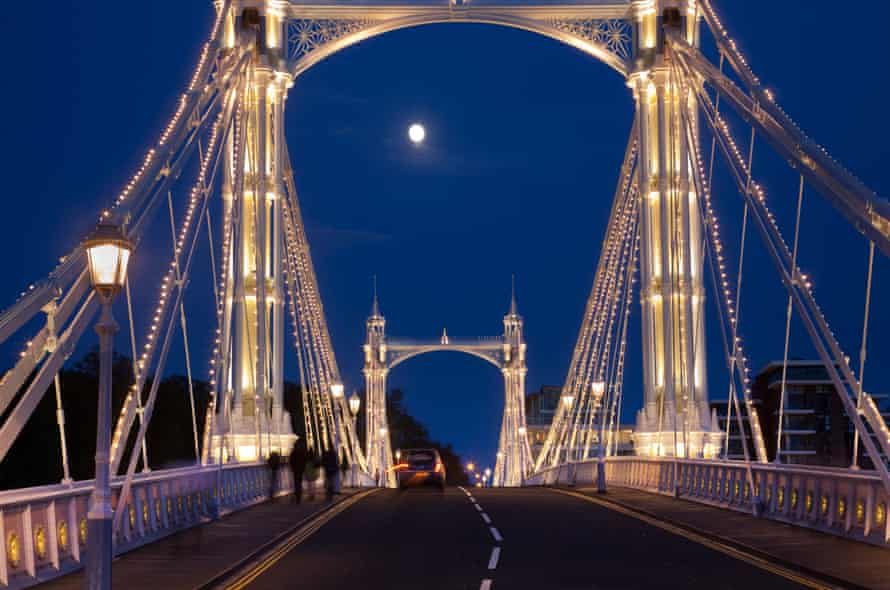 Albert Bridge across the Thames in London, festooned with lights and the moon shining through the night sky behind.