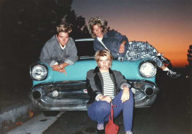 Surfers Jodi Cooper, Toni Sawyer and Pam Burridge sitting on a classic car with the sunset behind them in the 80s.