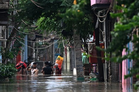 Flood-affected people carrying their belongings wade through flood water after river Yamuna overflowed following heavy monsoon rains in New Delhi.