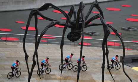 Lotto Dstny riders pass underneath the Mama spider sculpture during the team presentations at the Guggenheim museum in Bilbao.
