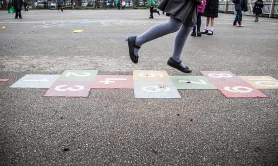 Schoolgirl playing hopscotch in the playground of a primary school