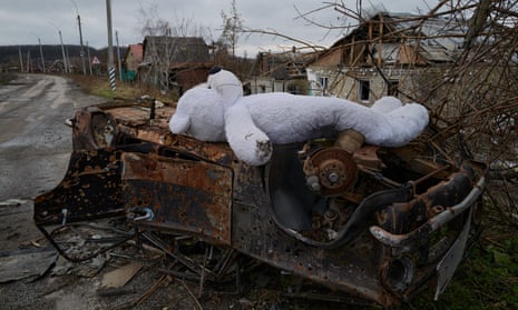 A large teddy bear lays on a burned vehicle in Bohorodychne, Ukraine.