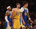 Luka Doncic reacts after a foul, flanked by two Warriors players on court