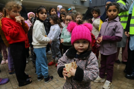 Displaced children from southern Lebanon eat manakish in the playground of a school turned into a shelter in Beirut.