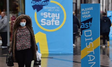 A shopper in Belfast passes public health advice billboards.