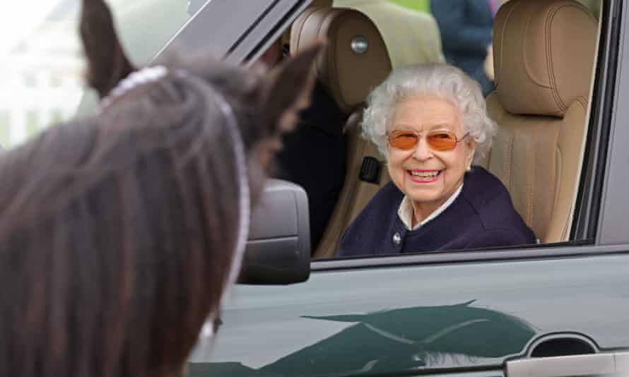 The Queen smiles from the passenger seat of her vehicle at the horse show