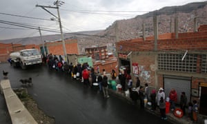 Bolivian citizens stand in line to get water.