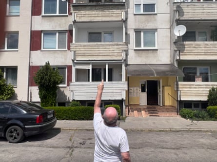 Mile L’udovit with his back to the camera points upwards in front of the 70s apartment block