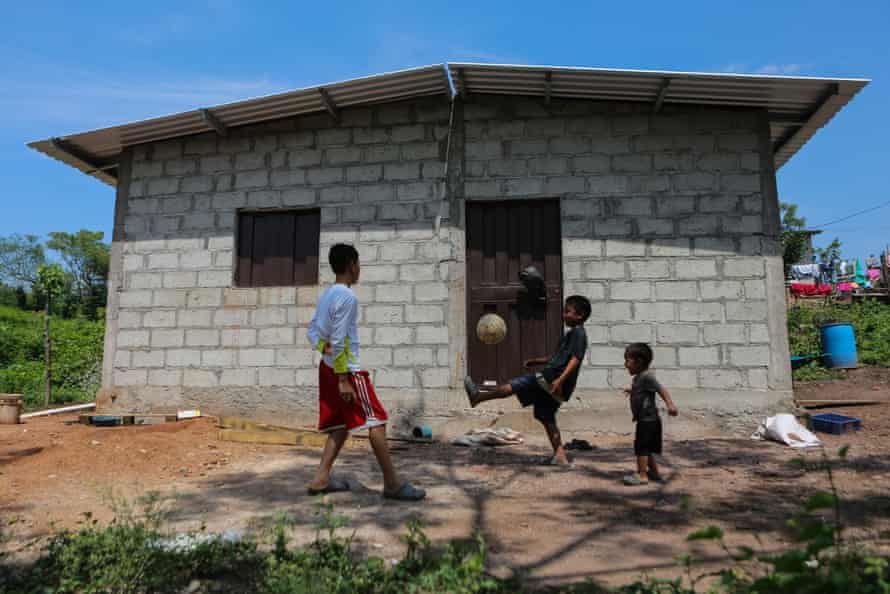 Three children play football outside a house in Honduras