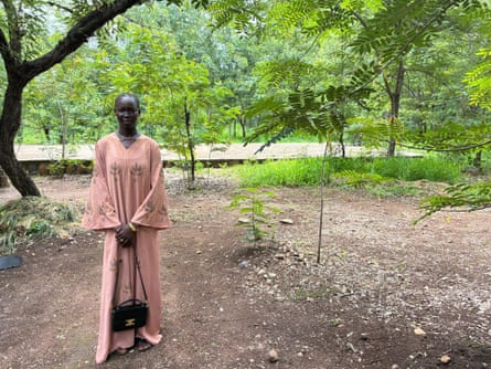 A woman stands in a leafy landscape