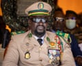 Mamady Doumbouya watches over a parade dressed in military uniform with medals