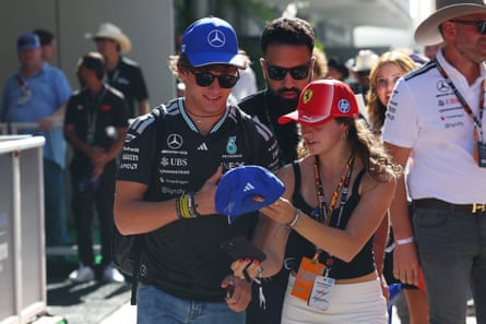 Andrea Kimi Antonelli signs a blue cap for a fan amid a crowd
