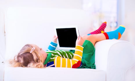 Little toddler girl with tablet pc relaxing on a white couch
