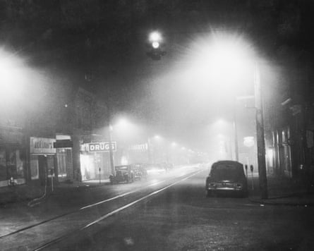 A black and white image of a smog filled street in 1940s America