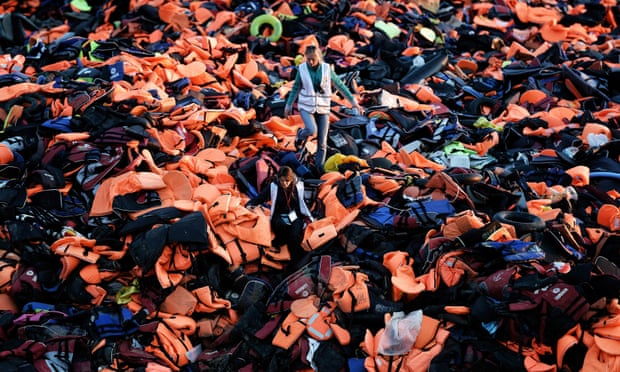 Volunteers walk on a pile of life jackets on the island of Lesbos.