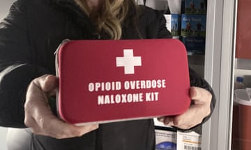 A woman holds a kit marked 'Opioid Overdose Naloxone Kit'