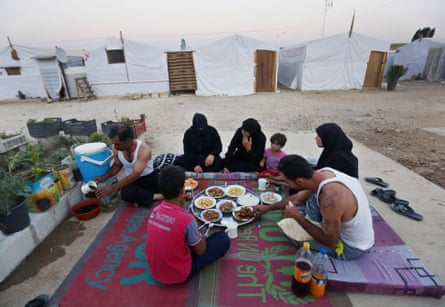 A Syrian family eat a meal outside their tent at a Syrian refugee camp in the Bekaa valley, Lebanon.