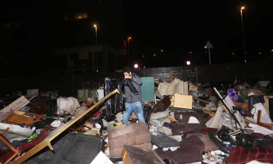 A man searches through flood damaged property left in a car park in Rochdale.