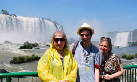 A young man with two older women pose in front of some waterfalls