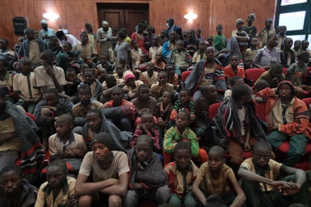 A large group of schoolboys sit and stand together in a crowded hall
