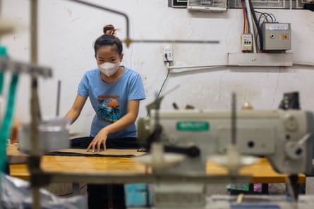 Worker in a face mask standing at a bench, with a sewing machine in the foreground