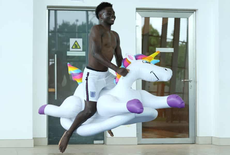 Bukayo Saka of England jumps into the swimming pool on an inflatable unicorn at St George’s Park on July 04, 2021 in Burton upon Trent, England