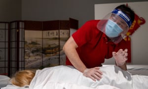 Zhen Wan of YW Massage wears gloves and face masks as he massages a customer in Yuba City.